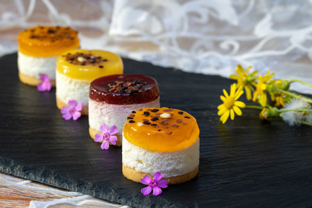 Colorful mini cakes on black slate plate with flowers, selective focusの写真素材