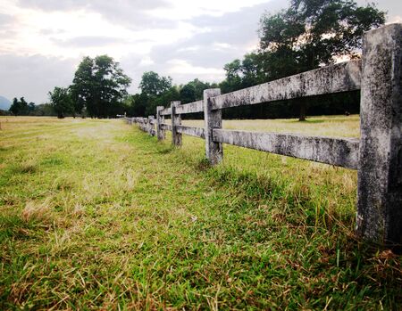 landscape with long cement fence on grass with sky backgroundの写真素材