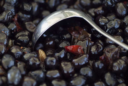 Black olives with red pepper and ladleの写真素材