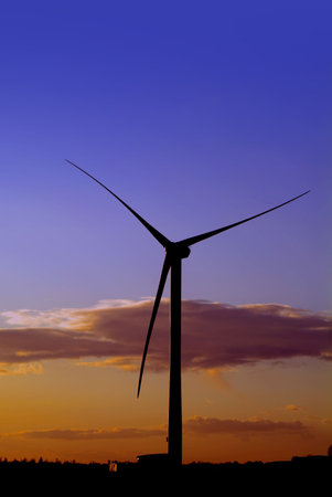 Single wind power generator against dramatic sunrise or sunset