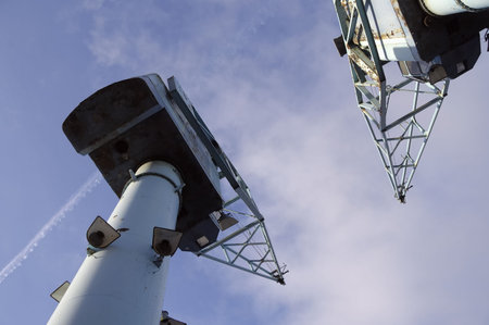 Low-angle view of two old rusty dock cranes against blue sky. Salford, Manchester, England