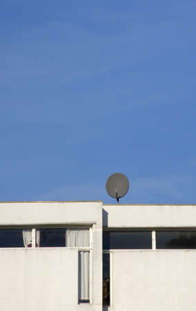 Single television satellite dish on white building against clear blue skyの写真素材