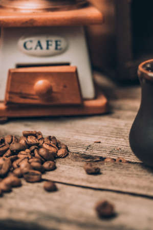 Manual coffee grinder and scattering of coffee beans on a wooden backgroundの写真素材