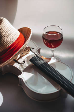 White violin with a straw hat with red piping and a glass of red wineの写真素材
