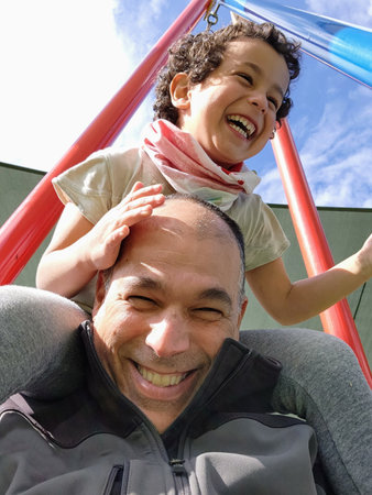 Father and son having fun at the playground. They are smiling and happy.の写真素材