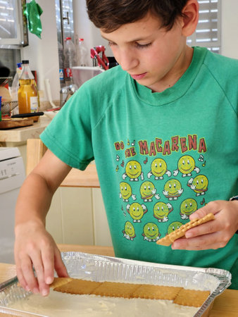 A young boy baking cookies in the kitchen.  He is wearing a green t-shirt.の写真素材