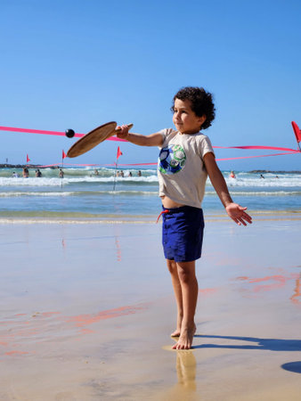 boy playing on the beach with a racket and a ball in his handの写真素材