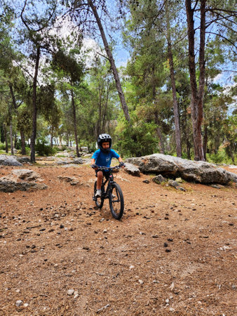 young Cyclist Riding the Bike on the Trail in the Pine Forestの写真素材