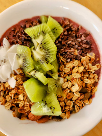 Muesli with kiwi and chocolate in a white bowlの写真素材