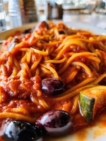 Spaghetti with tomato sauce and olives on a white plate.の写真素材
