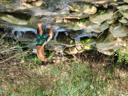 Young man walking in a water stream on a hot summer day.の写真素材