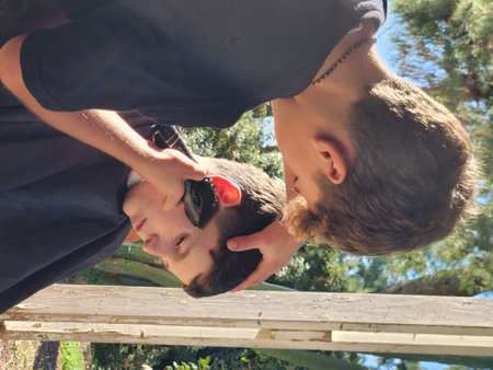 Teenage boy cutting a boys hair on a sunny dayの写真素材