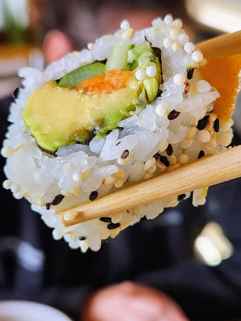 Sushi roll with salmon, avocado and cucumber on wooden chopsticksの写真素材