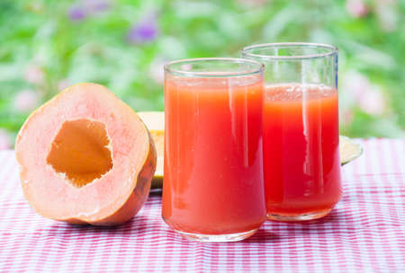 Smoothie papaya juice on table with garden flower backgroundの写真素材