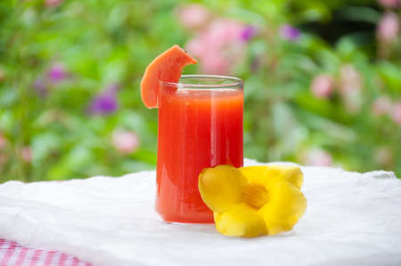 Smoothie papaya juice on table with garden flower backgroundの写真素材