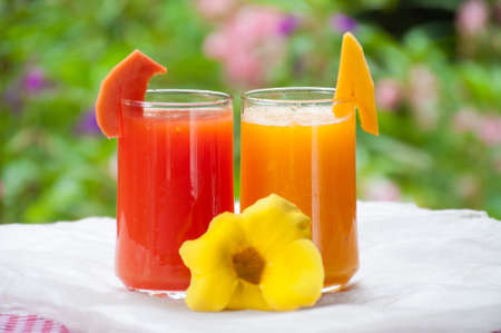Smoothie papaya juice on table with garden flower backgroundの写真素材