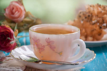 Hot tea cup and sweet pastry on wooden table with green nature background, tea time conceptの写真素材