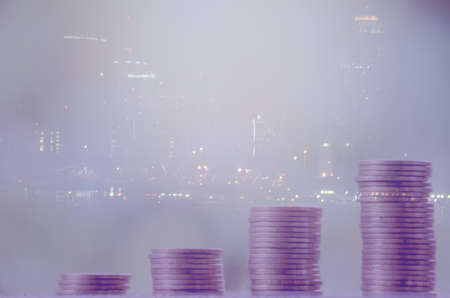 Double exposure of city and rows of coins, finance and saving conceptの写真素材