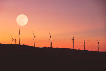Full moon with turbines field against sunset skyの写真素材