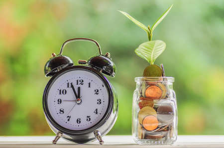 Alarm clock and jar of coinsの写真素材