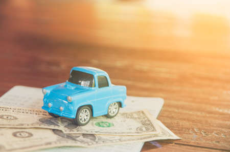 Miniature car with money and book bank statement on wooden backgroundの写真素材