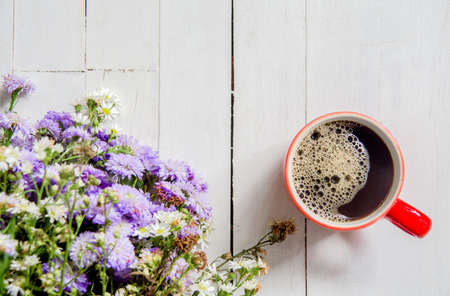 Red cup of black coffee with flowers on white wooden background with copy space for textの写真素材
