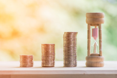 coins and hour glass with nature background, time for money saving conceptの写真素材