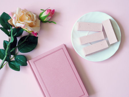 Book, tea, rosary, sweets on a plate on a pink background. Flower. The concept of Ramadan, iftar.