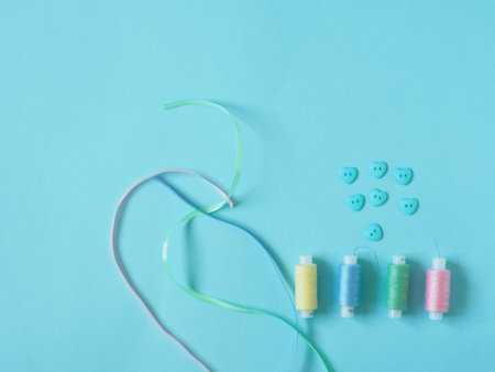 Spools of thread, buttons. Accessories for sewing on a blue background. Set for needlework in the...