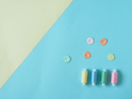 Spools of thread, buttons. Accessories for sewing on blue and yellow background. The Duo's...