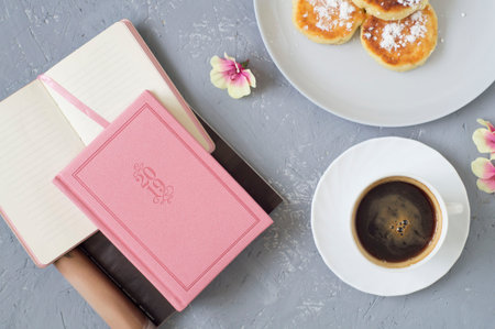 The concept of women's desktop. A Cup of coffee, decorative flowers, a note and a notebook, glasses. Morningの写真素材