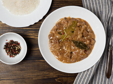 Beef goulash-delicious goulash in a white plate on a wooden white table. Filipino cuisine-Adobo...