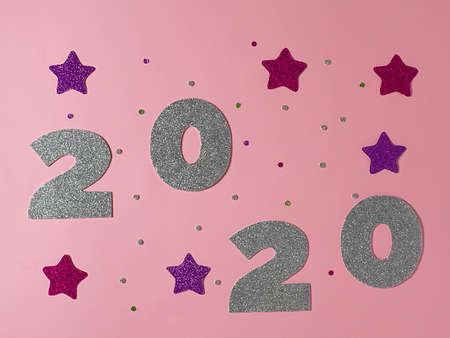 Celebrating the new year 2020. Silver mother-of-pearl paper, number 2020 with pink stars and confetti on a pink background.Flat lay.の写真素材