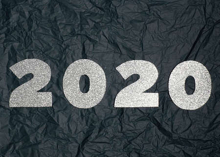 Celebrating the new year 2020. Silver mother-of-pearl paper, number 2020 on a dark crumpled background.Flat lay.の写真素材