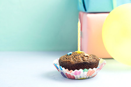 Birthday cupcakes with candles on a green and blue background.