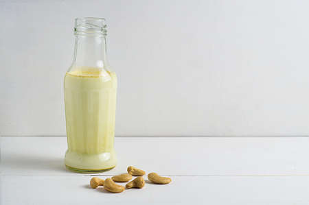 Cashew milk with cashew nuts on a white wooden background. Healthy food. Vegan. Copy space.の写真素材