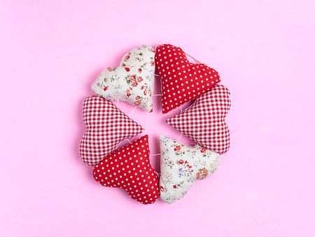 Wreath of textile soft hearts on a pink background. Valentines day hearts made of cotton fabric are...