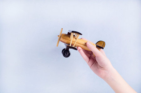 The hand of the child with a wooden hand-made aircraft.