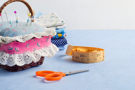 Fabrics, threads and pins on a blue background. Concept of needlework, sewing. Handmade work. Copy...