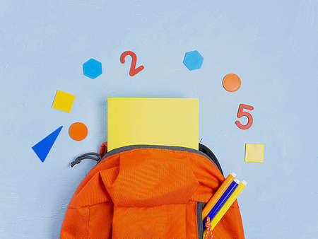Orange backpack with school supplies on a blue concrete background. The concept of the school.の写真素材