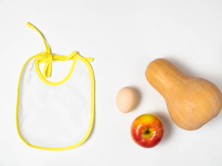 Bib, baby puree, spoon, Apple, egg. The view from the top, flat lay.The concept of healthy nutrition...