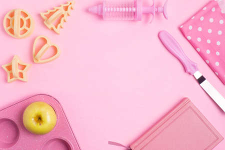 Cupcakes baking dish, a spatula, a recipe book, a towel on a pink concrete background. Monochrome. Copy space. Flat lay.の写真素材