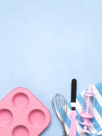 Cake pan, spatula, whisk, towel on a blue concrete background. A copy of the space.