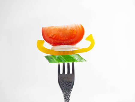 Fork with vegetables on a white background.の写真素材