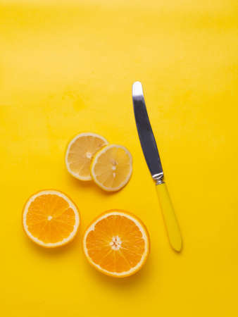 Orange and lemon and yellow knife on a yellow background.の写真素材