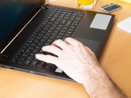 Laptop, mans hands, home furnishings, juice, books. The concept of working online, learning online.