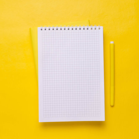 White Notepad and yellow pen on a yellow background. Minimalism. Copy space.