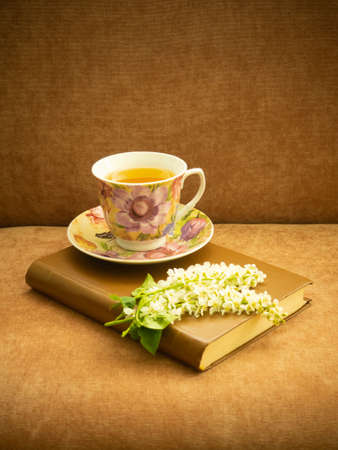 An old hardcover book and tea in a Cup on a brown background. Vintage.の写真素材