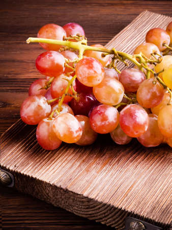 A brush of red grapes on a dark wooden tableの写真素材
