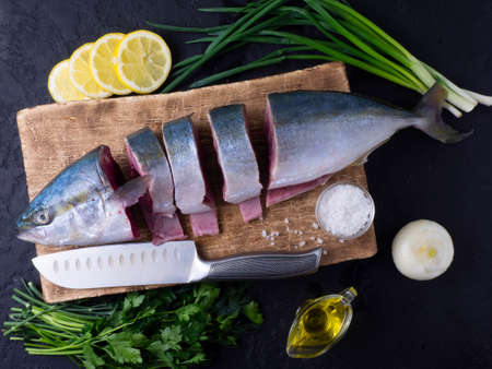 Fish raw fresh tuna with lemon slices, herbs, salt on a dark background. The concept of healthy eating and dieting.の写真素材